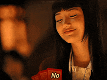 a woman is holding a red card that says no