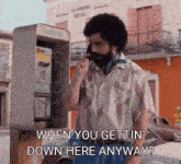 a man talking on a pay phone with the words " when you gettin ' down here anyway "