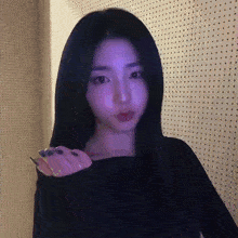 a young woman with long black hair is standing in front of a wall with holes in it .