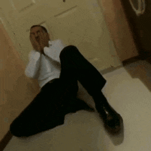 a man in a white shirt and black pants is laying on the floor