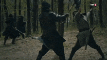 a group of people are standing around a man with a sword in his hand .