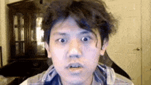 a young man with a messy haircut is making a funny face while looking at the camera .