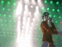 a man is singing into a microphone in front of a green background