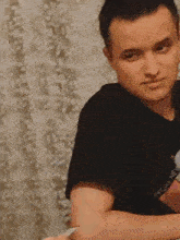 a man wearing a black t-shirt that says journey is sitting at a table .