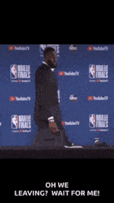 a man in a suit is standing in front of a nba finals banner