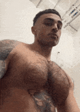 a shirtless man with a tattoo on his chest is standing in a shower .