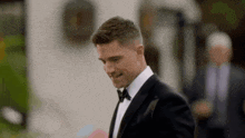 a man in a tuxedo is smiling while walking