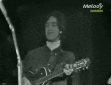 a man is playing a guitar in front of a microphone in a black and white photo .