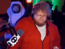 a man in a red jacket is dancing in front of a microphone in a room .