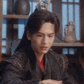 a man in a costume is sitting at a table in front of a window .