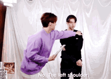 a man in a purple shirt is pointing at another man 's left shoulder .
