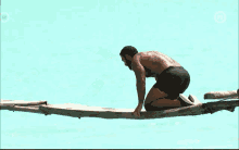 a shirtless man is kneeling on a rope in the ocean with the number 12 on the bottom right