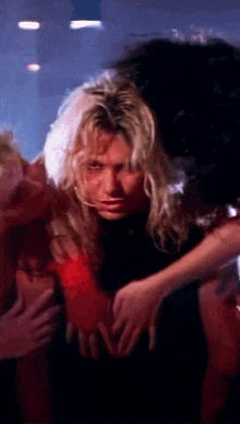 a man with long blonde hair is surrounded by other people