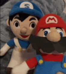 two stuffed mario and luigi dolls are sitting next to each other .