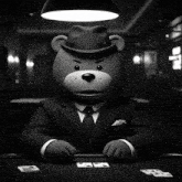 a teddy bear in a suit and fedora holding a bunch of cards