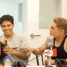 two men are sitting in front of a microphone with a sign that says zky on it
