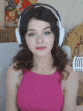 a woman in a pink top is wearing headphones