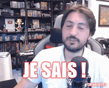 a man sitting in front of a microphone with the words je sais written on his chest