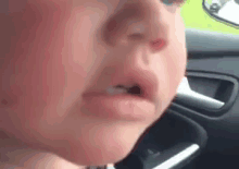 a close up of a baby 's face in a car with a tear coming out of his nose .