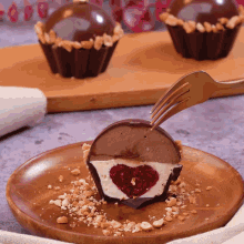 a cupcake with a heart shaped filling is cut in half on a wooden plate