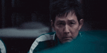 a man in a green and white jacket is looking at the camera .