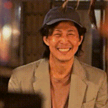 a man wearing a suit and hat is smiling .