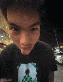 a young man wearing a black t-shirt with a picture of a man sticking his tongue out