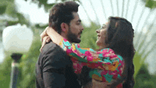 a man is holding a woman in his arms and they are kissing .