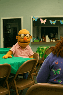 a puppet is sitting at a table with a green tablecloth