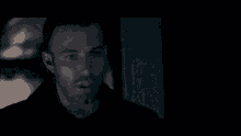 a close up of a man 's face in a dark room looking at the camera .