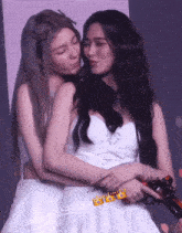 two women are hugging each other with a crown on the bottom right corner