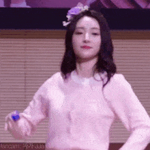 a woman in a pink shirt is dancing in front of a window .
