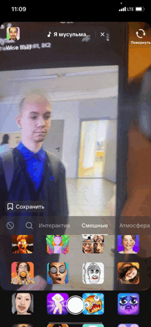a phone screen shows a man in a blue shirt and black suit