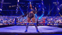a woman is standing in a wrestling ring with a belt on .
