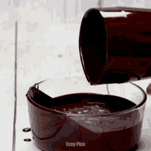 a cup of chocolate is being poured into a bowl that says easy plus on the bottom