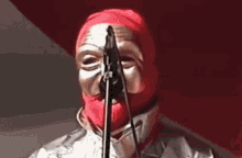 a person with a red mask on their face is singing into a microphone