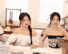two women sitting at a table with one wearing a black top with the number 68 on the front