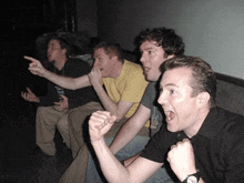 a group of men are sitting on a couch with one wearing a watch