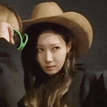 a woman wearing a cowboy hat and sunglasses is being photographed by a man .
