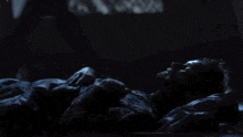 a man is laying in bed in the dark with a blanket on his chest .