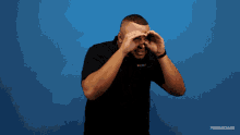 a man covering his eyes with his hands in front of a blue background that says xperimental