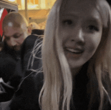 a woman with blonde hair is smiling in front of a man