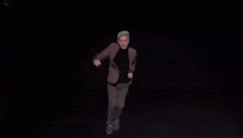 a man in a suit and black shirt is dancing in the dark