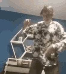 a man in a floral shirt is dancing in front of a shelf .