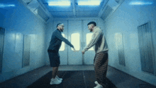 two men are dancing in a room with blue lights behind them