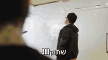 a man in a leather jacket stands in front of a white board that says ' !! ' on it