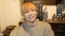 a man is smiling in front of a sign that says " shots "