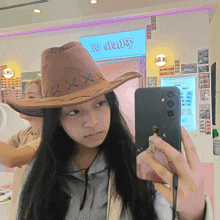 a woman wearing a cowboy hat takes a selfie in front of a sign that says 10 oolong