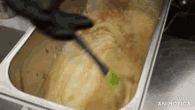 a container of food is being stirred with a spatula and the words made in animatica are on the bottom