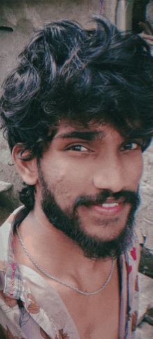 a man with a beard and a floral shirt is smiling for the camera